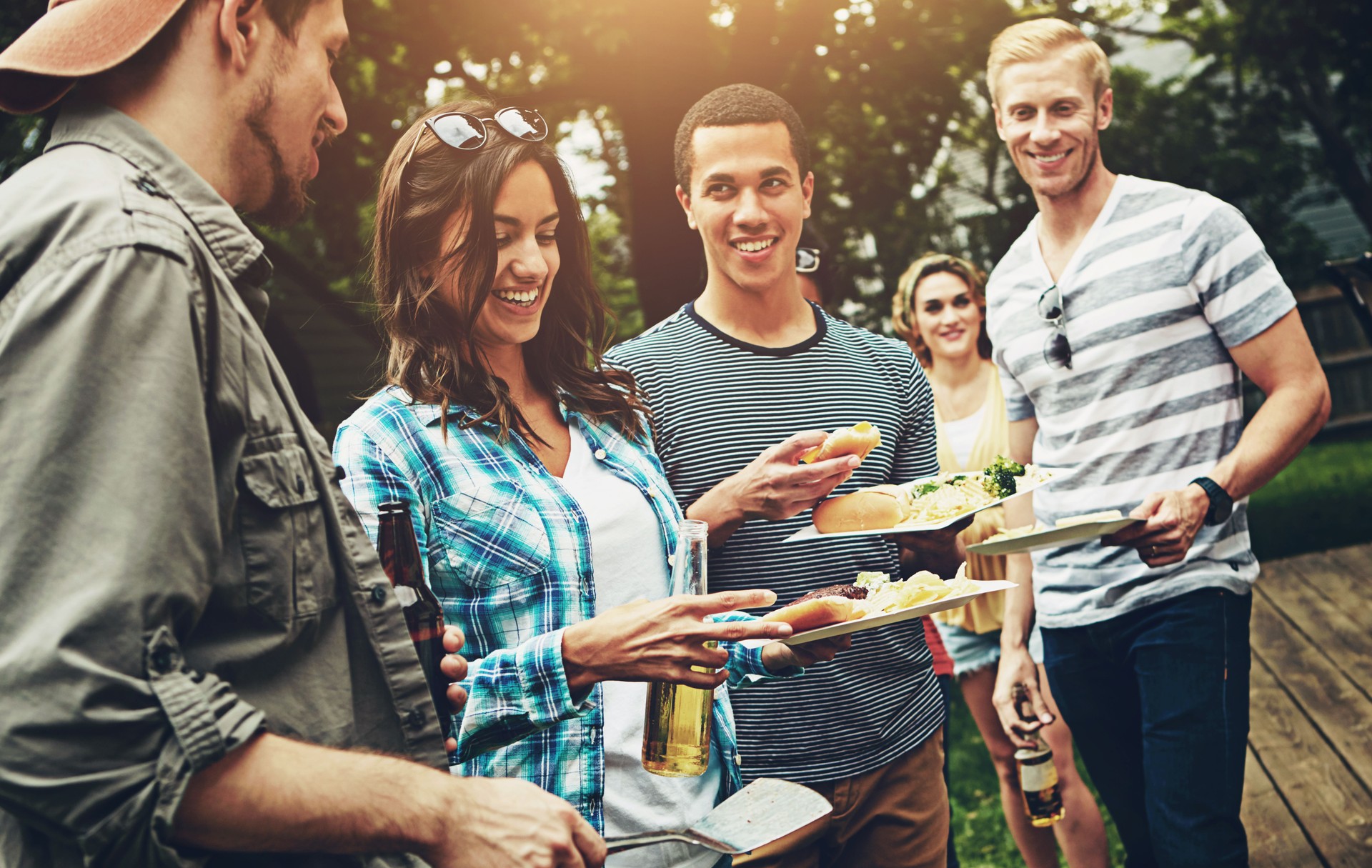 Friends, drinks and barbecue with food for party, picnic or reunion with alcohol in America. Group, people and cheerful at bbq in backyard, summer and vacation for holiday, celebration or birthday